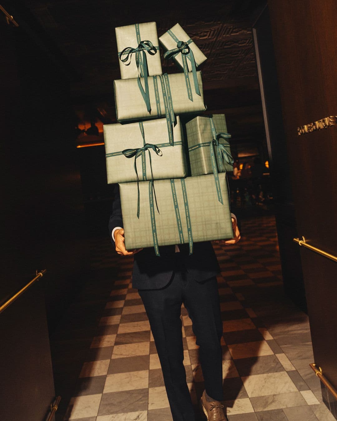 A person carrying a stack of ribbon-tied corporate gifts